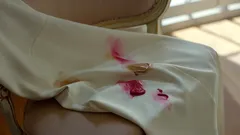 Macchia di rossetto rosso su tessuto bianco su una sedia, illuminazione naturale.